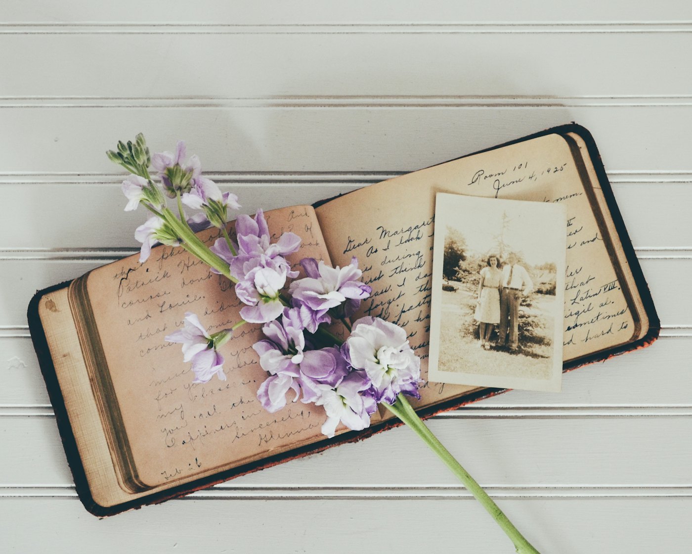 An old handwritten notebook with a photograph and flowers
